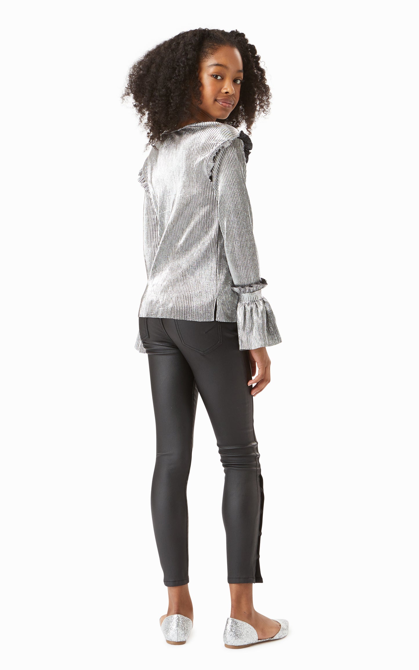 Back view of girl wearing metallic silver long-sleeve top with leather-look skinny jeans. 