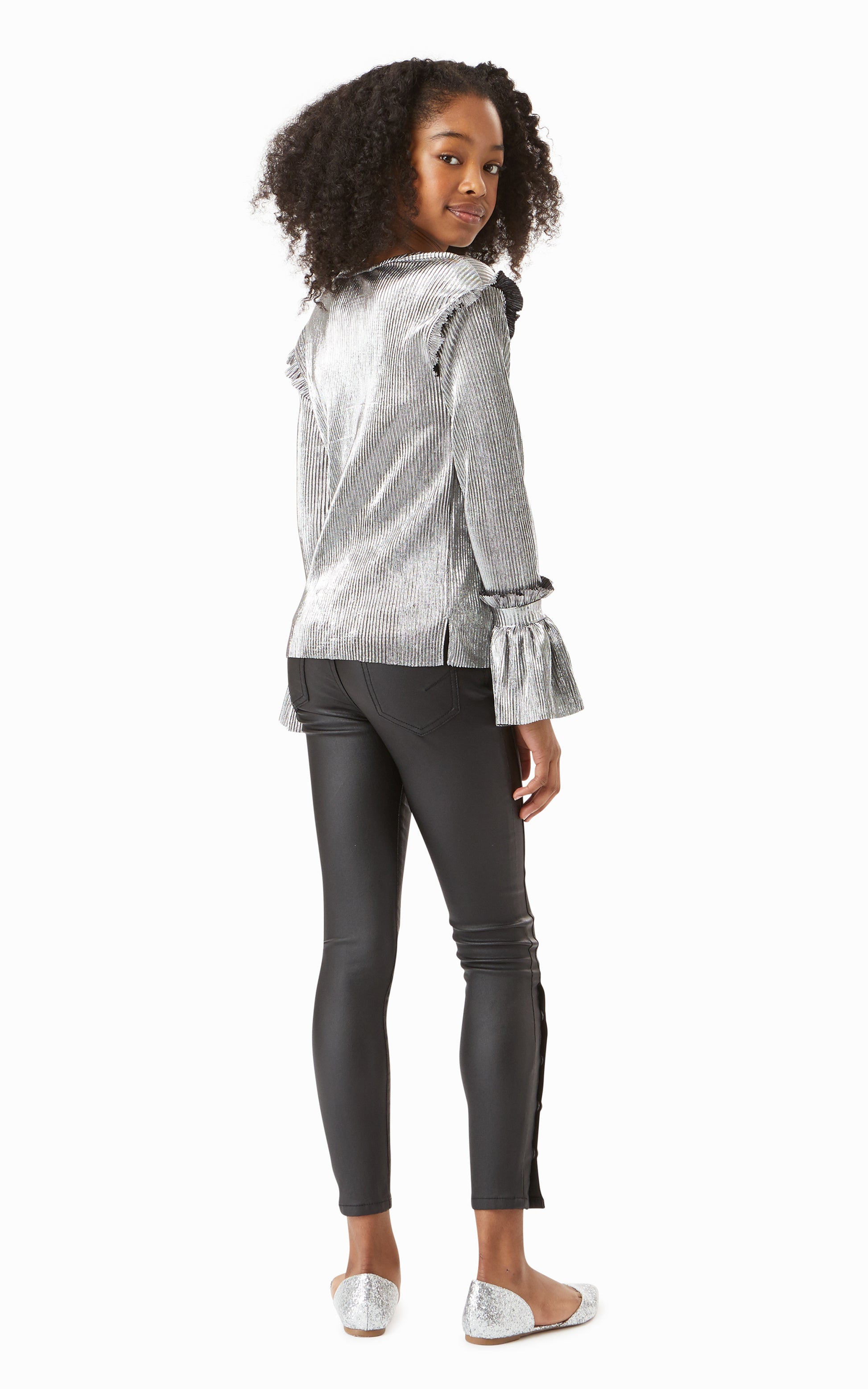 Back view of girl wearing metallic silver long-sleeve top with leather-look skinny jeans. 