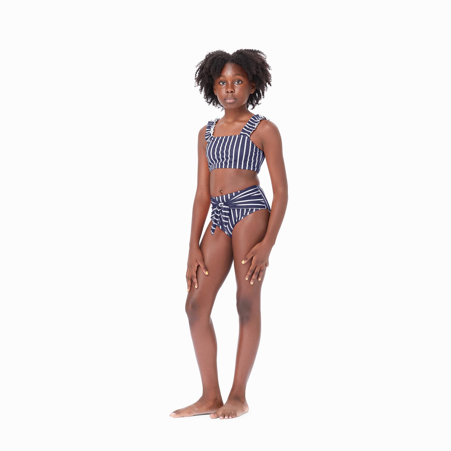 Girl wearing navy two-piece swimsuit with white stripes and bow