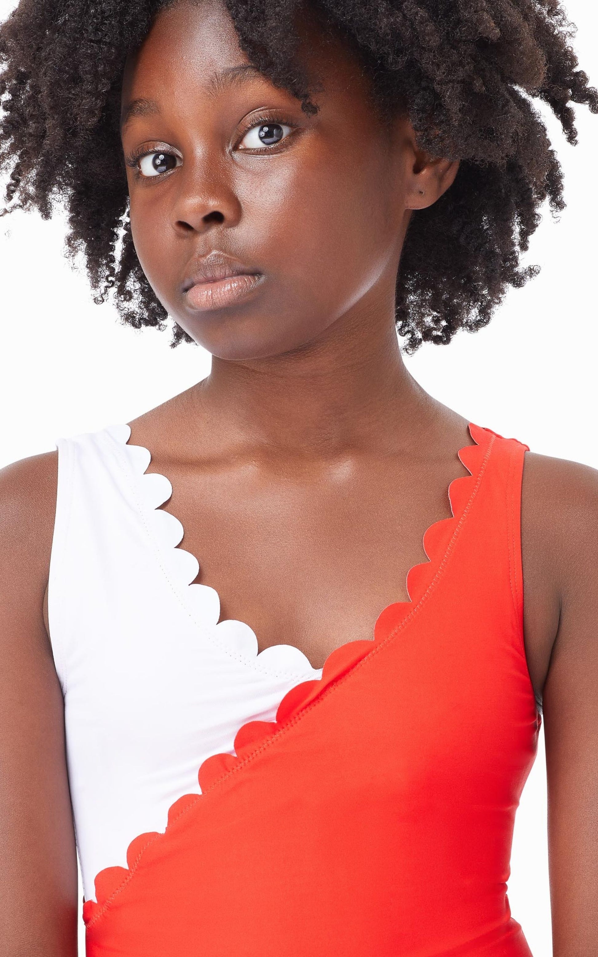 Close up of young girl wearing red-and-white color block one-piece swimsuit with scalloped trim