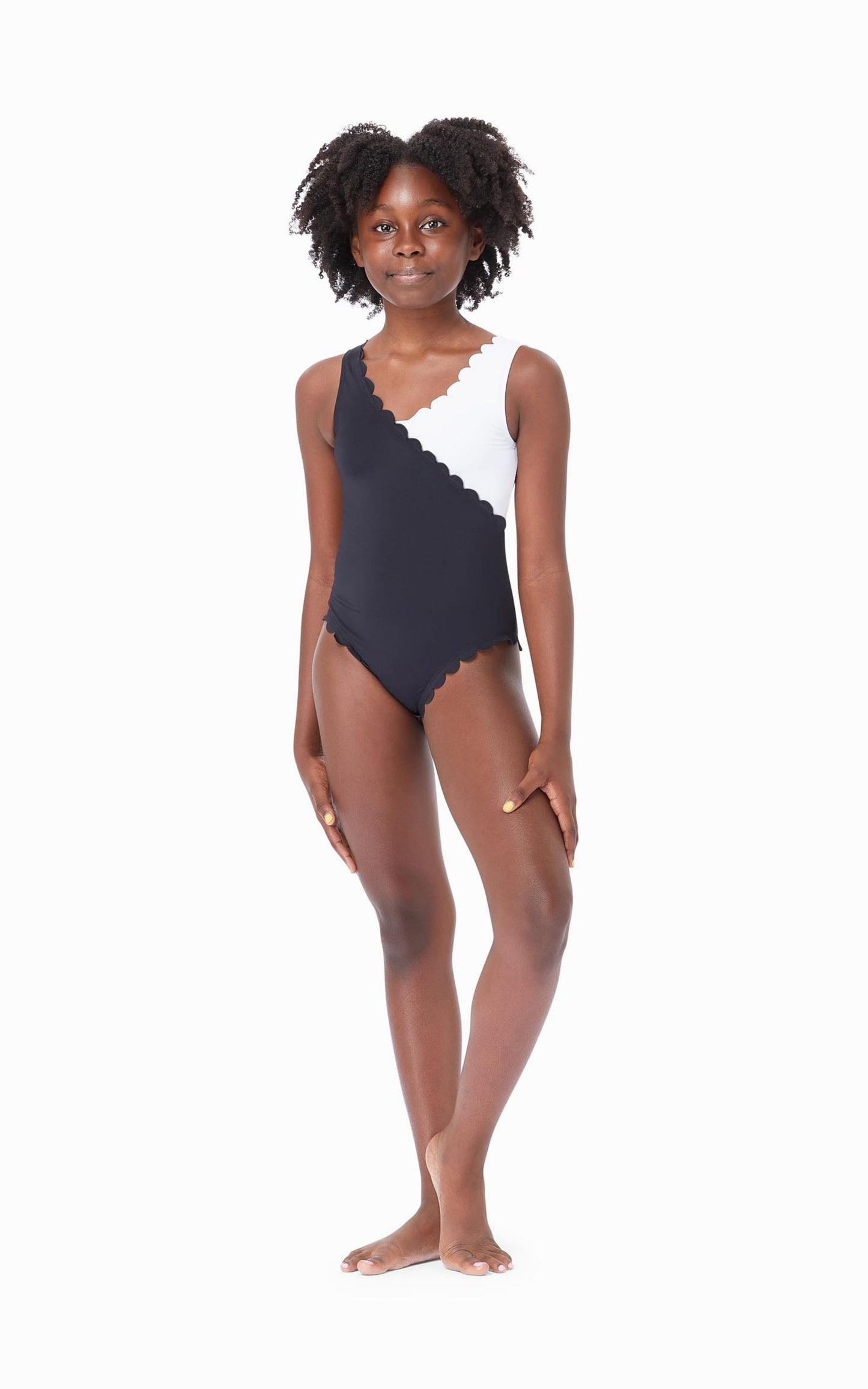 Young girl wearing black-and-white color block one-piece swimsuit with scalloped trim