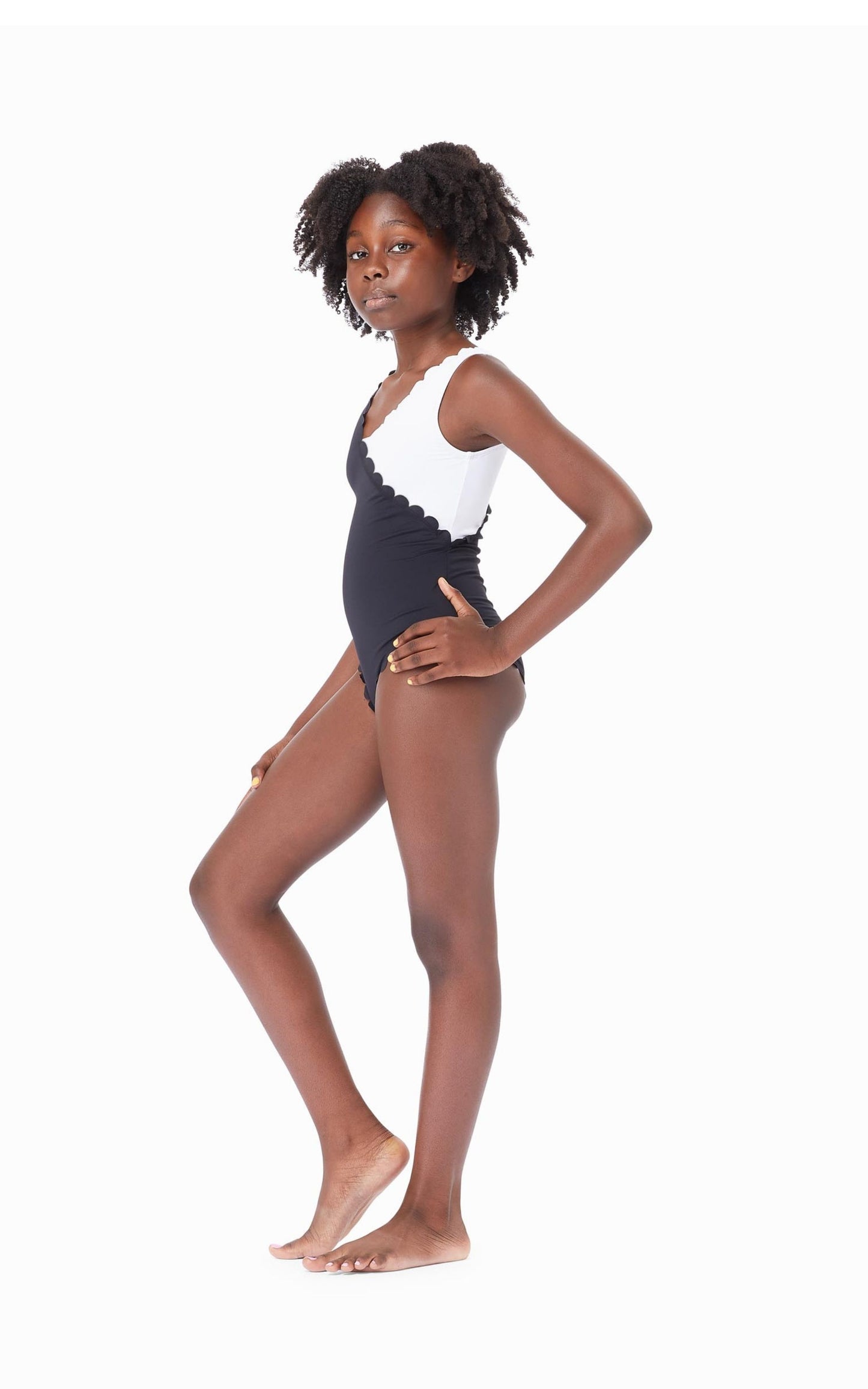 Young girl wearing black-and-white color block one-piece swimsuit with scalloped trim