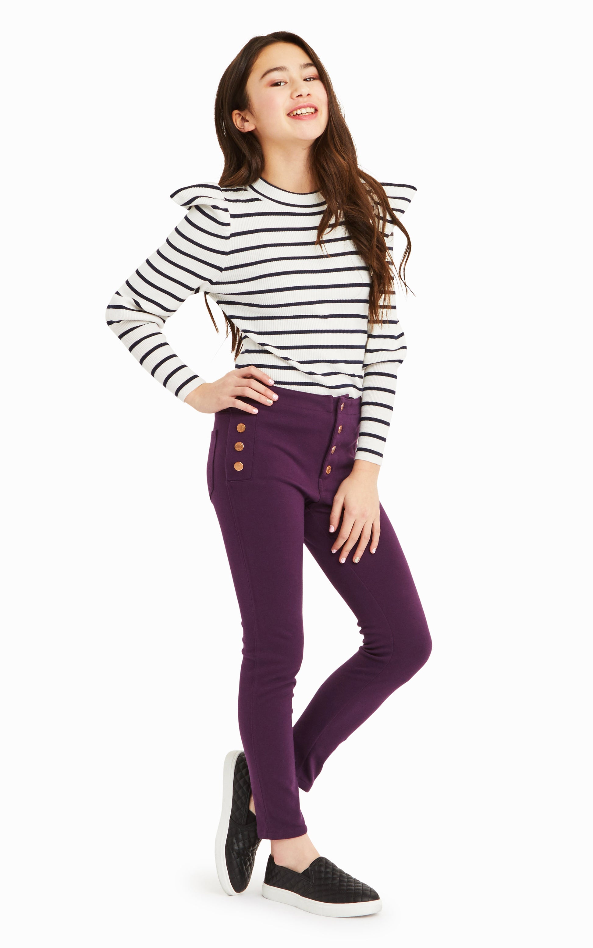 Side view of girl wearing white and black-striped long-sleeve top with purple snap-front pants.