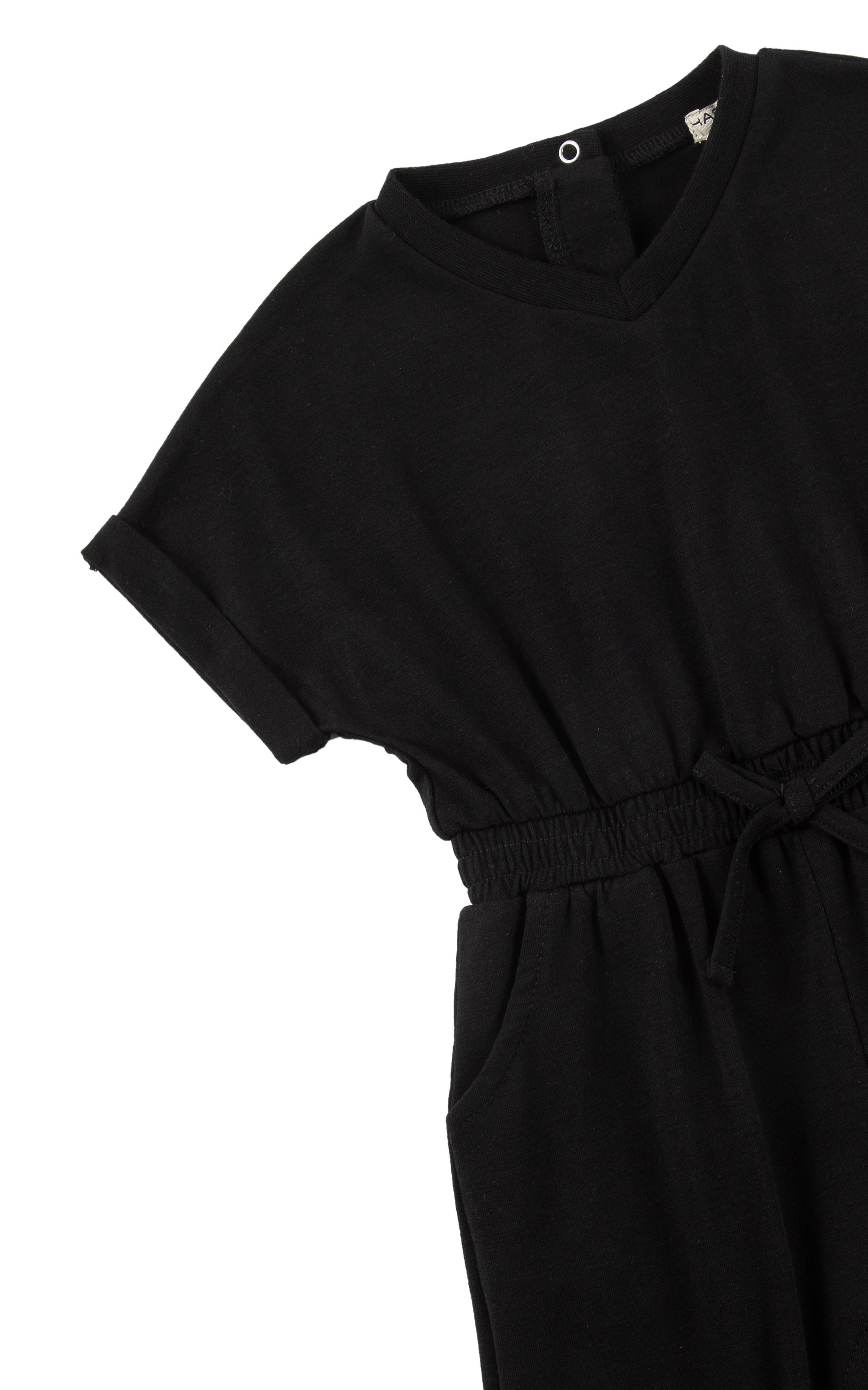 Close up of sleeve and tie waist on black romper with folded cuff.