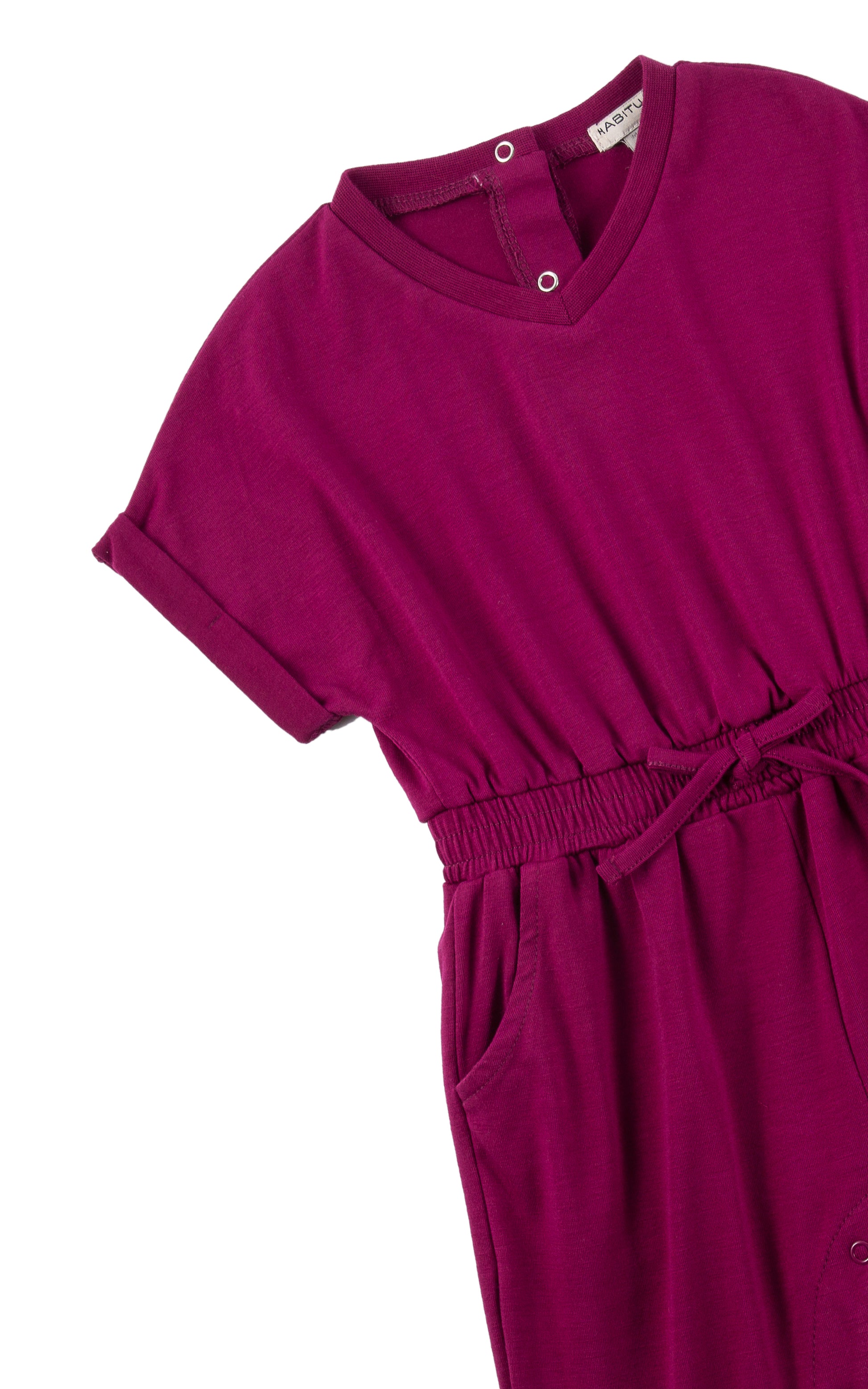 Close up of sleeve and tie waist on plum-colored romper with folded cuff.