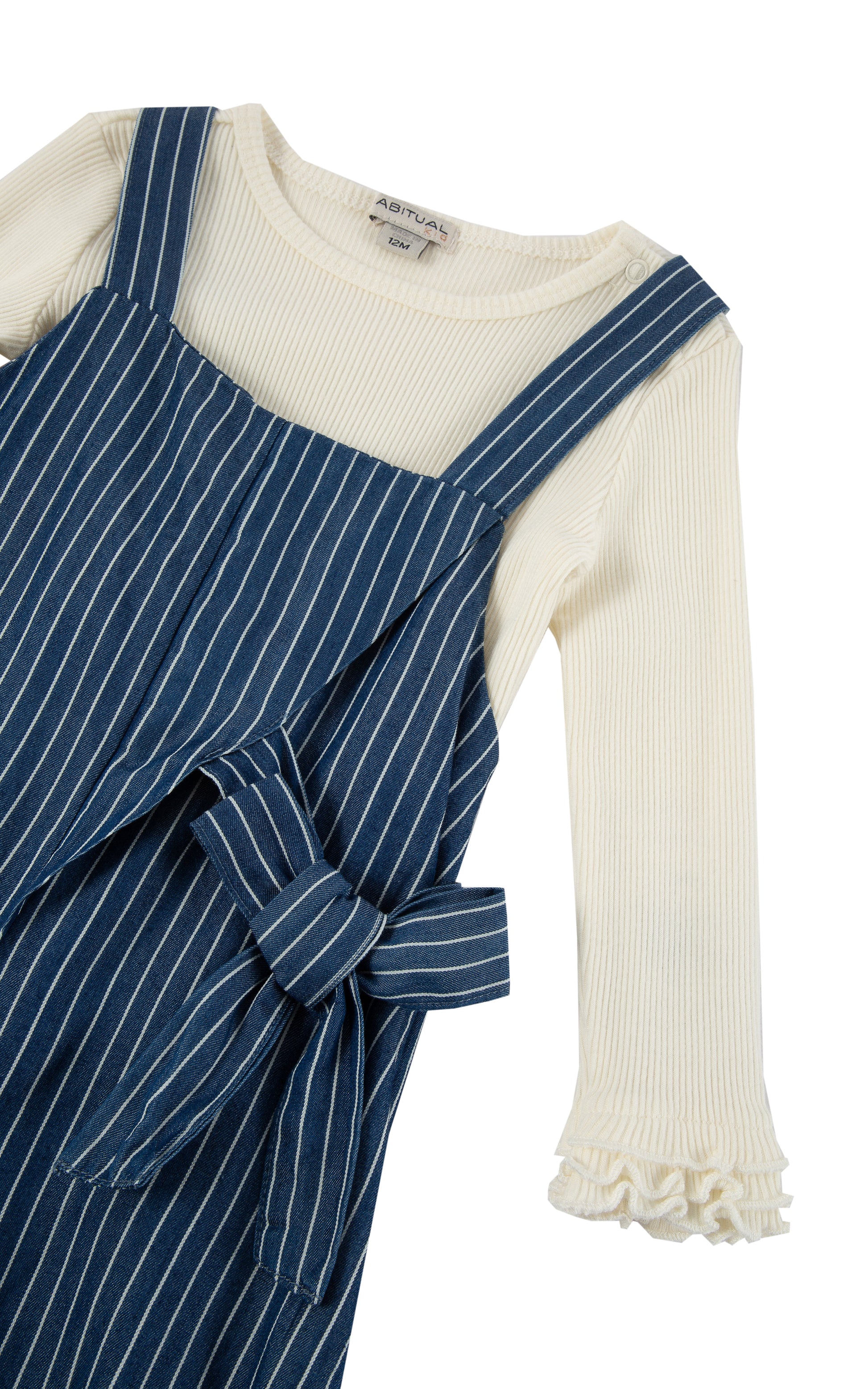 Close up of top portion of blue with white pinstripe overalls and white long-sleeve top with ruffles at cuff.