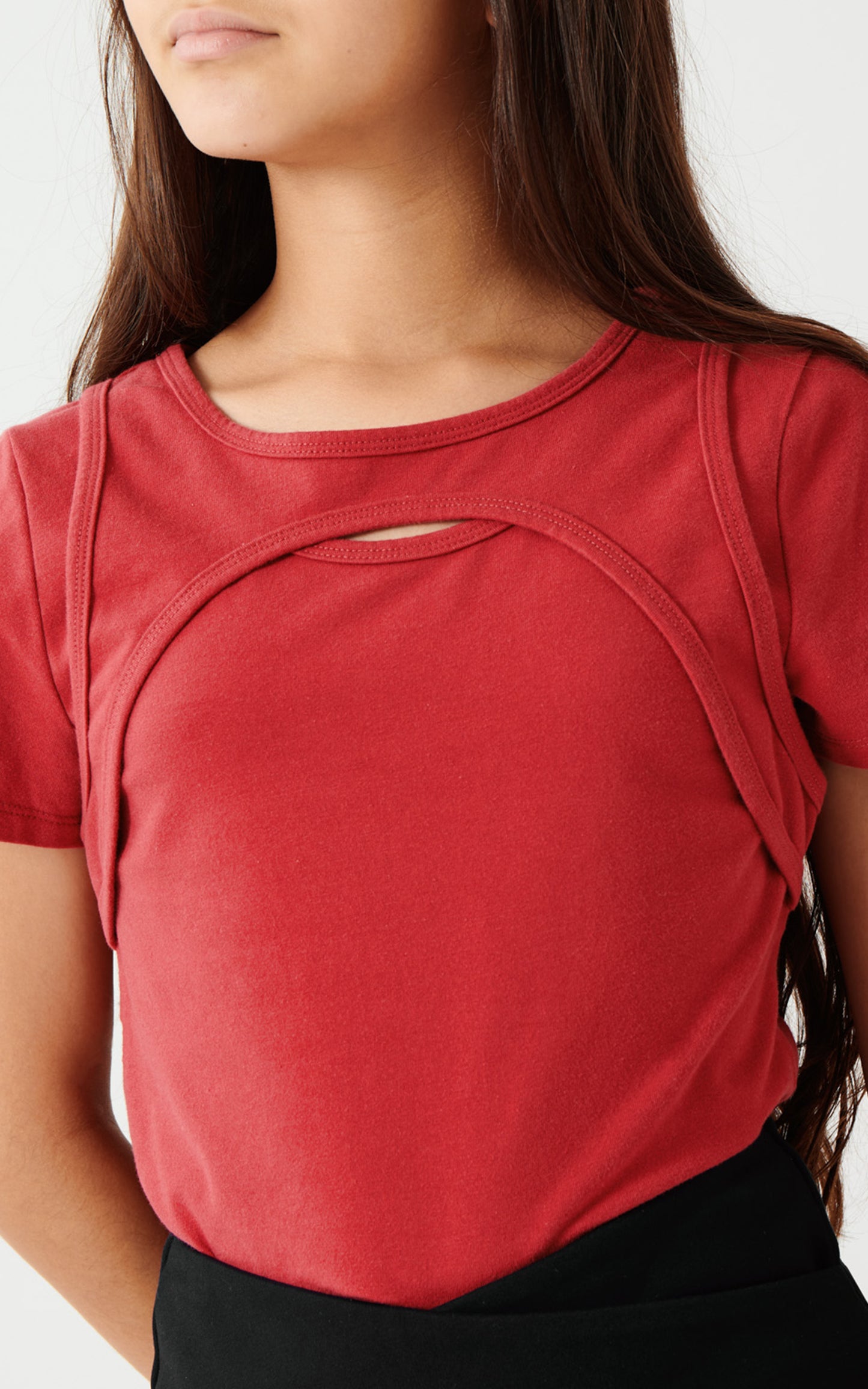 GIRL WEARING DARK RED SHORT SLEEVE TOP WITH A SMALL KEYHOLE CUT-OUT AT THE UPPER BODICE