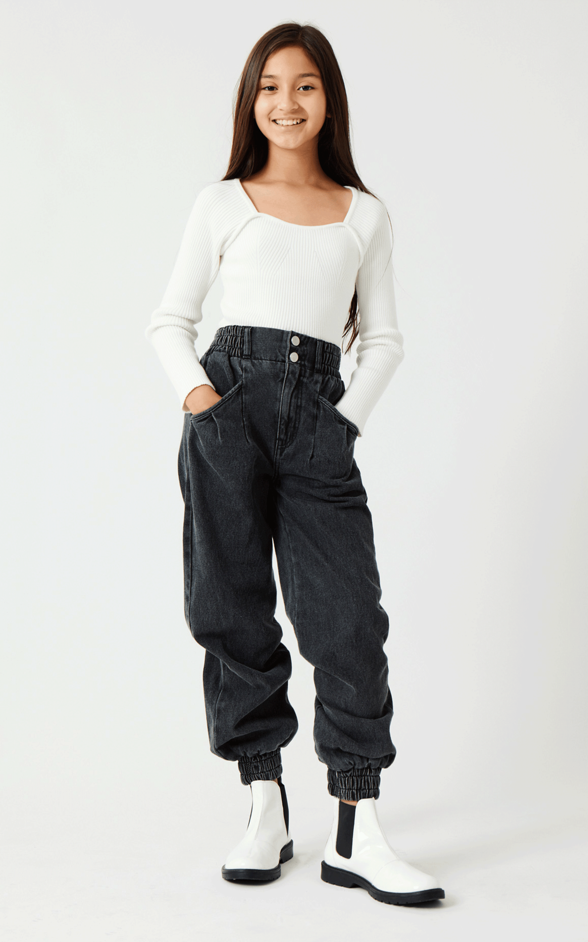 GIRL IN WHITE LONG-SLEEVE RIBBED SHIRT AND WASHED OUT BLACK DENIM PANTS WITH RUCHED ELASTIC WAISTBAND AND CUFFED ANKLES